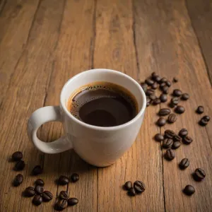 Espresso macchiato w szklance oraz cappuccino z latte art na drewnianym stole w kawiarni.